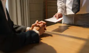 Pracownik wręcza dokument szefowi, sygnalizując rezygnację ze stanowiska kierowniczego.