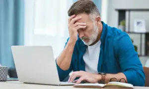 Zmartwiony mężczyzna przy laptopie, zastanawia się, czy można zwolnić pracownika na L4.