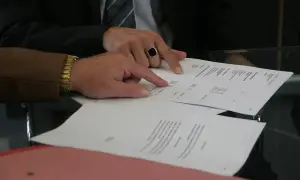 Dłonie wskazujące na dokumenty na stole.