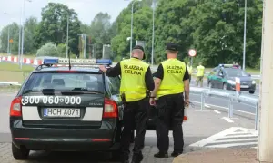 Funkcjonariusze Służby Celno-Skarbowej w kamizelkach odblaskowych przy radiowozie. Ich praca to nie tylko służba, ale też zarobki.