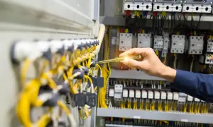 Elektryk sprawdza instalację elektryczną. Dokumentacja ZUS wykaz stanowisk pracy w szczególnych warunkach może być potrzebna przy pracach z takim okablowaniem.