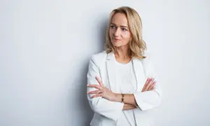 Profesjonalne zdjęcie do CV: kobieta w białej marynarce, z rękami skrzyżowanymi na piersi, patrzy w bok.