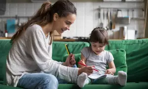 Uśmiechnięta mama pomaga dziecku w rysowaniu. Wspólna praca dla dzieci, rozwijająca kreatywność i więź.