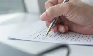 Dłoń pisze długopisem na kwestionariuszu osobowym dla pracownika.
