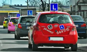 Czerwony samochód nauki jazdy z literą "L" na dachu. Zastanawiasz się, ile zarabia instruktor jazdy?