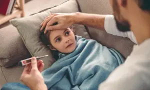 Ojciec mierzy gorączkę chorej córce. Niestety, ten urlop z powodu siły wyższej trwa dłużej niż planowano.