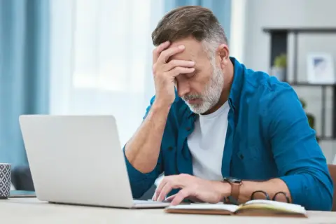 Zmartwiony mężczyzna przy laptopie, zastanawia się, czy można zwolnić pracownika na L4.