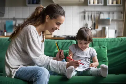 Uśmiechnięta mama pomaga dziecku w rysowaniu. Wspólna praca dla dzieci, rozwijająca kreatywność i więź.