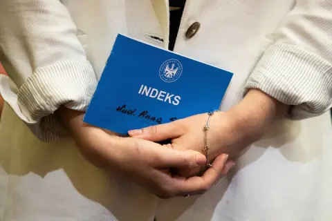Kobieta trzyma indeks, zastanawiając się, czy studia liczą się do emerytury.