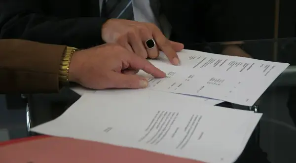 Dłonie wskazujące na dokumenty na stole.