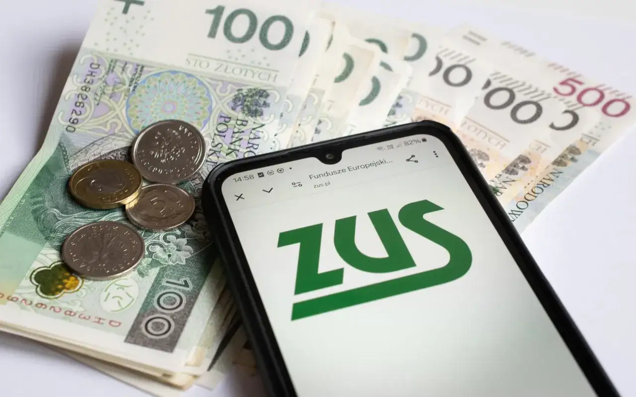 Na ekranie telefonu widnieje logo ZUS, obok polskie banknoty i monety. Sprawdzasz, do którego rocznika obowiązuje emerytura pomostowa.