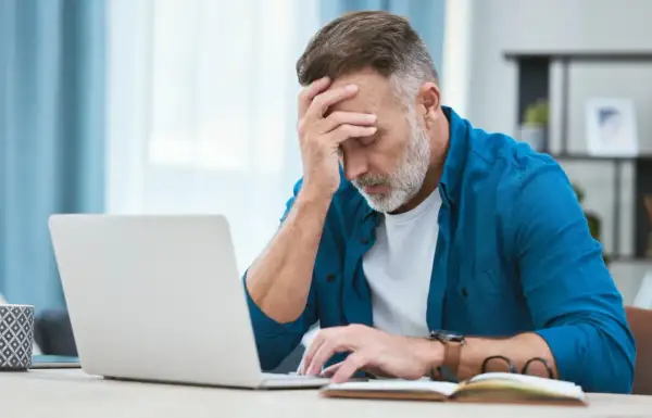 Zmartwiony mężczyzna przy laptopie, zastanawia się, czy można zwolnić pracownika na L4.