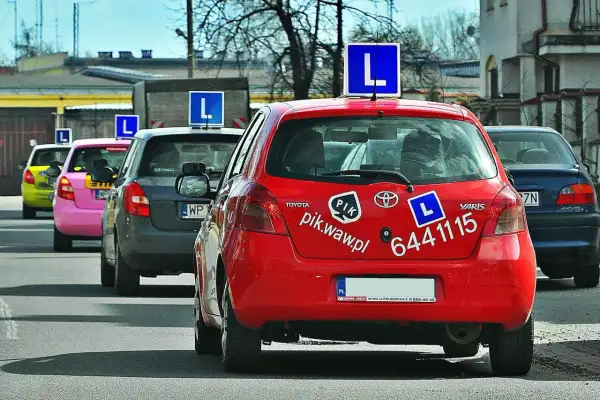 Czerwony samochód nauki jazdy z literą "L" na dachu. Zastanawiasz się, ile zarabia instruktor jazdy?